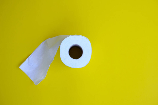 Tuvalet kağıdı sarı arkaplanda yuvarlanıyor  - Fotoğraf, Görsel