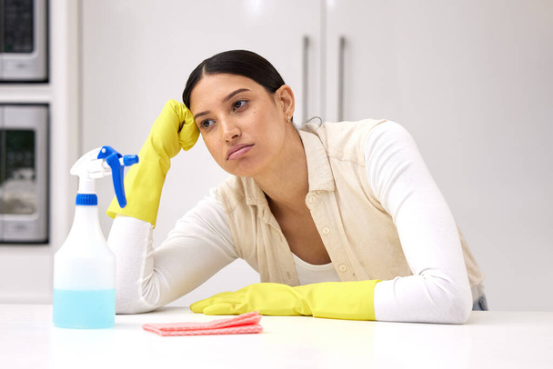 una giovane donna che sembra infelice mentre fa le faccende domestiche. - Foto, immagini
