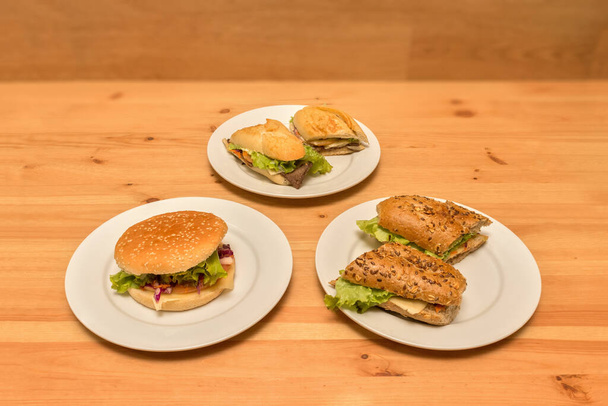 Chicken sandwich, beef, and cheeseburger. On wooden background - Photo, image
