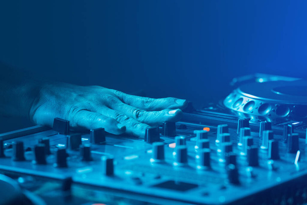 DJ, dysk dżokej mieszania muzyki z niebieskim światłem. Widok z przodu - Zdjęcie, obraz