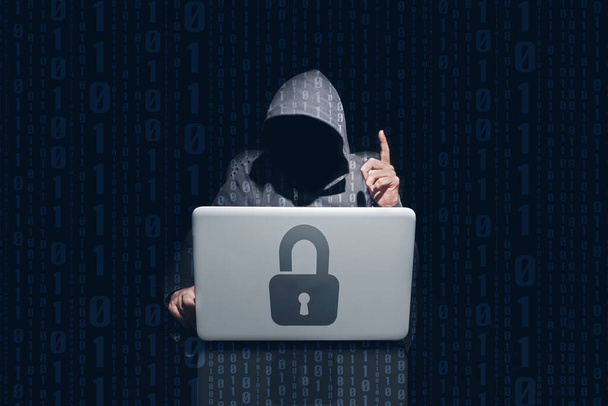 Anónimo hacking y utilizando ordenador contraseñas de pirata con el símbolo del candado en el portátil. Fondo oscuro y binarios 0 y 1 - Foto, imagen