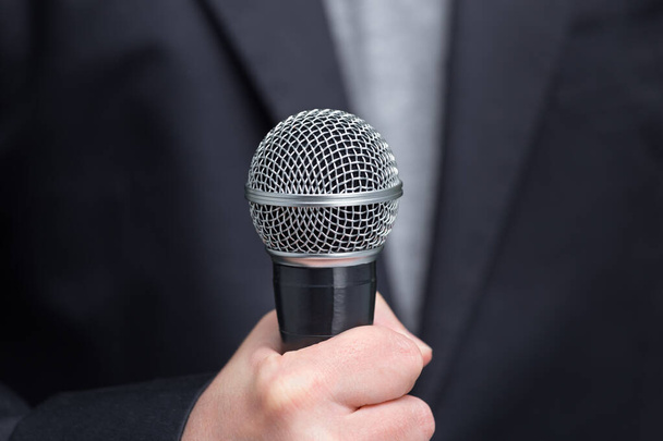 Entrevistador ou jornalista com microfone na mão em primeiro plano, mic. Vista frontal - Foto, Imagem