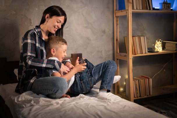 boldog család anya és gyermek fia tabletta este lefekvés előtt pihentető otthon. Családi koncepció. - Fotó, kép