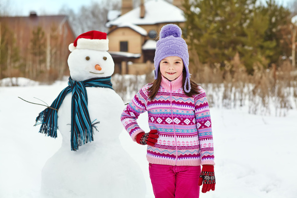 kid playing with snowman - Foto, afbeelding