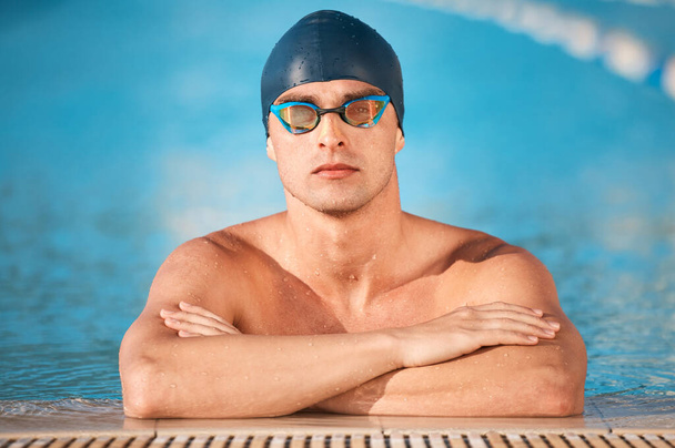 Ένας όμορφος νεαρός αθλητής κολυμπά σε μια πισίνα ολυμπιακού μεγέθους.. - Φωτογραφία, εικόνα