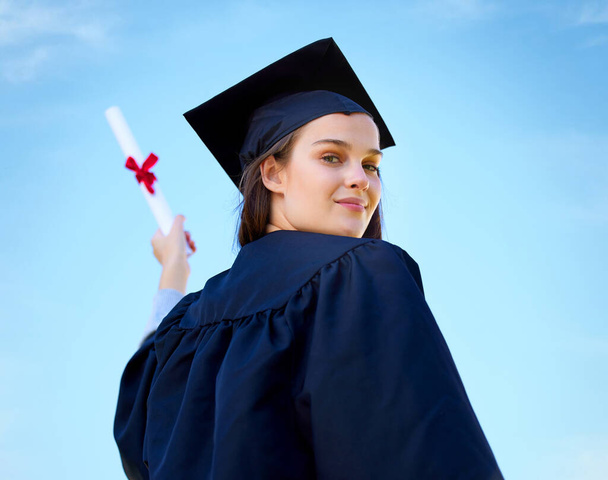 Portrait of a young woman cheering with her diploma on graduation day. - Valokuva, kuva