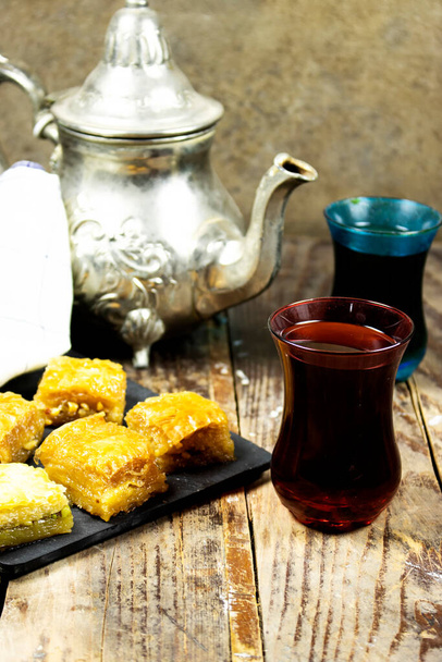 Pistachio baklava dessert with teapot on wood table. Traditional Turkish cuisine delicacies - Foto, imagen