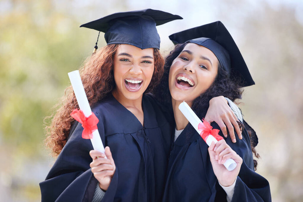 Portrait of two young women holding their diplomas on graduation day. - Фото, изображение