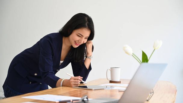 Alegre jovem asiático feminino freelancer de pé em casa moderna escritório e usando tablet digital. - Foto, Imagem