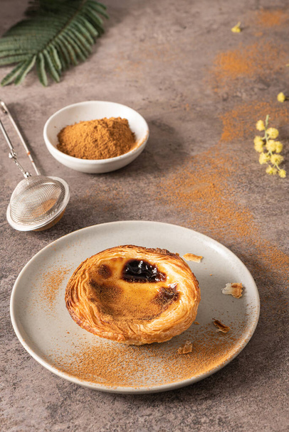 Traditional Portuguese pastry Pastel de Nata or Pastel de Belem served with cinnamon powder in a traditional tray on a rustic board. Egg tart - Photo, Image