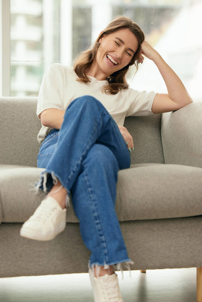 egy fiatal nő ül egy kanapén otthon. - Fotó, kép