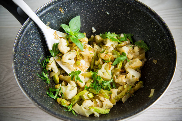 cauliflower fried with zucchini and vegetables in a pan with herbs - Фото, изображение