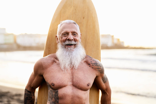 Hombre mayor en forma divirtiéndose surfeando en la playa tropical - Personas mayores saludables estilo de vida y concepto de deporte extremo - Foto, imagen