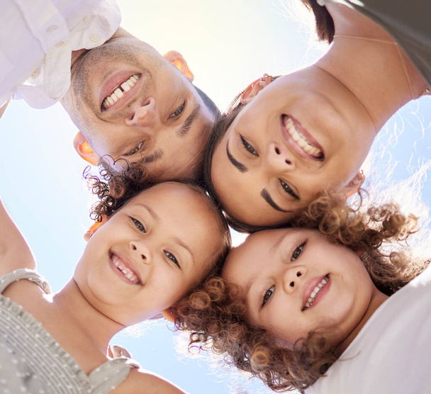 Low angle portrait of a happy young family huddled together on a fun day outdoors. - Zdjęcie, obraz