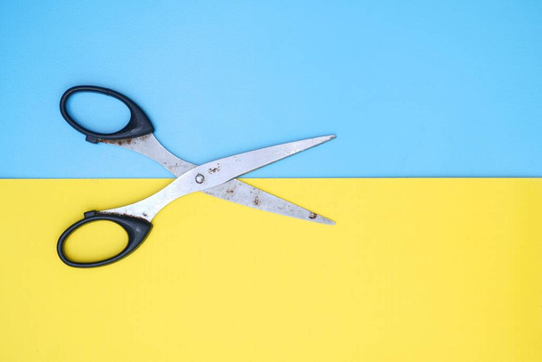 The scissors isolated on blue-yellow background with copy space - 写真・画像