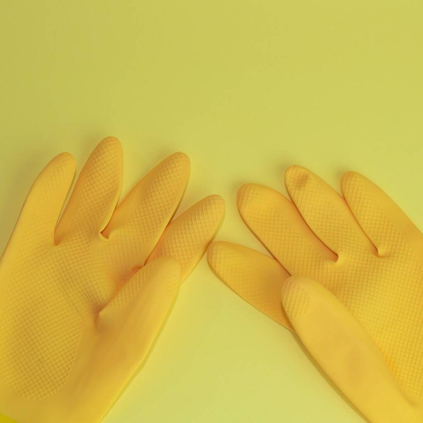 A closeup of a pair of yellow gloves on yellow background for copyspace - Foto, imagen