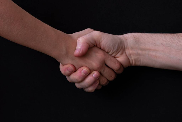 A closeup of a handshake on a black background - Fotografie, Obrázek