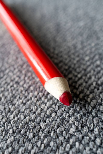 A vertical shot of a red pencil on a gray surface - Φωτογραφία, εικόνα