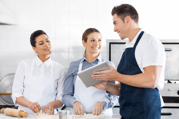 Happy Chefs Discussing Recipe On Digital Tablet In Kitchen - Photo, image