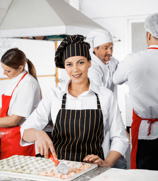 Smiling Chef Cutting Ravioli Pasta In Commercial Kitchen - Foto, Bild
