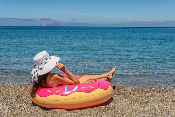 Happy woman with inflatable donut on a tropical beach. Summer vacation concept. - Photo, image