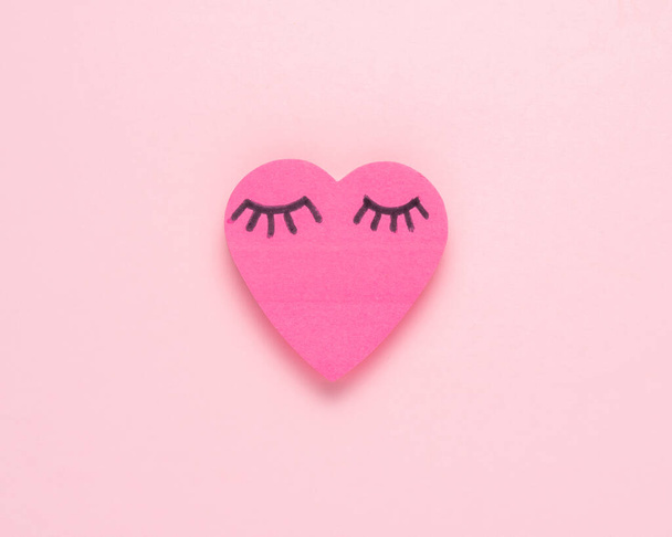 Heart shape pink paper with eyelashes. Valentines or woman's day background design. Minimal flat lay. - Фото, зображення