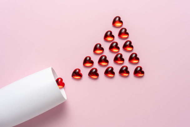 White champagne glass with red glass hearts over pink background. Minimal love concept. - Foto, immagini