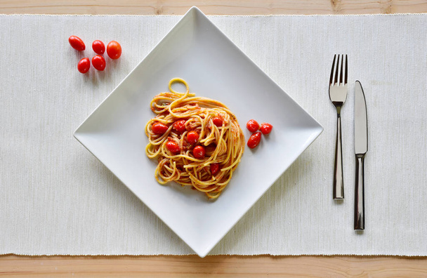 Espaguetis con tomates cherry servidos en un plato cuadrado y disparados desde arriba  - Foto, Imagen