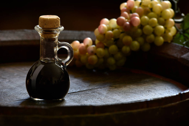 Traditional balsamic vinegar of Modena in a small bottle on a wooden barrel  - Foto, Imagen