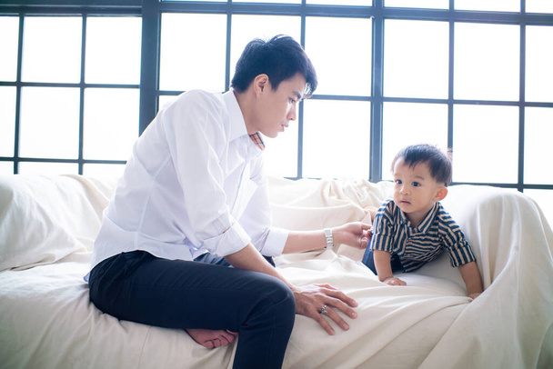 Γραφείο επιχειρήσεων πατέρας παίζει με το μικρό αγόρι μετά την εργασία γίνεται σε καναπέ στο άνετο δωμάτιο - Φωτογραφία, εικόνα