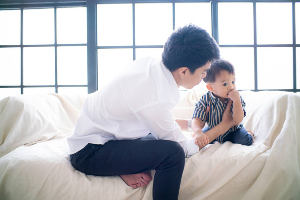 Oficina de negocios padre jugando con el niño después de trabajar hecho en el sofá en la habitación acogedora - Foto, imagen