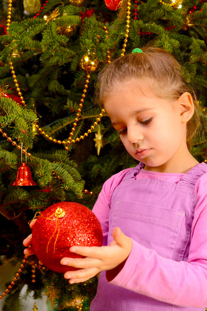 Schattig peuter meisje houden decoratieve Christmas speelgoed bal - Foto, afbeelding