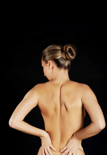 Back view of naked woman touching her back - Foto, immagini