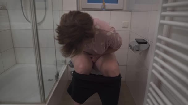 Woman sitting on toilet holding her stomach. Female suffers from diarrhea or diarrhea, stomach aches. Pain and problems with digestion. Hygiene, the concept of public health. Belly disease.  - Materiał filmowy, wideo