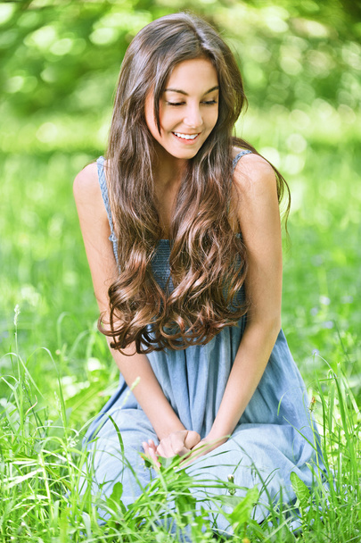 Lächelnde Frau sitzt auf grünem Rasen - Foto, Bild