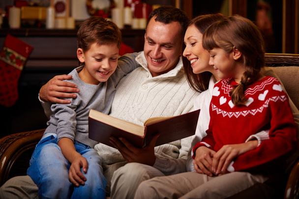 Family reading book on Christmas evening - Photo, Image