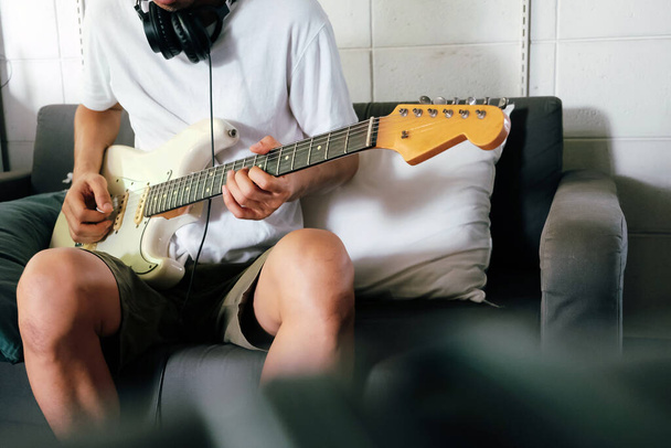 Άνθρωπος που παίζει ηλεκτρική κιθάρα στον καναπέ στο σπίτι - Φωτογραφία, εικόνα