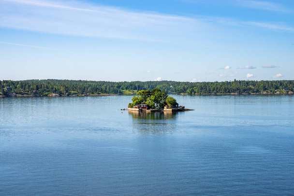 Distant view of summer houses on islands of Archipelago. Picturesque scenery of settlement amidst Baltic Sea against blue sky. Beautiful natural landscape with Swedish lifestyle. - Фото, зображення