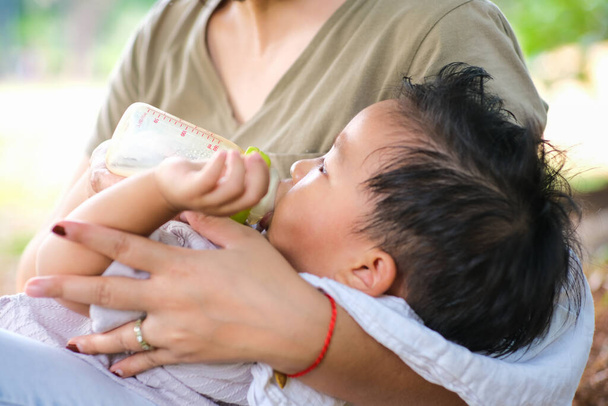 Batole dítě chlapec sát prsa mléko krmení maminka v parku venkovní příroda strom - Fotografie, Obrázek