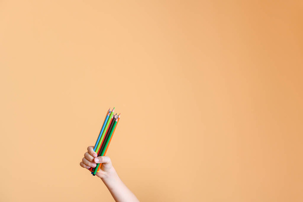 Child's hand raises a handful of colored pencils on yellow background. Concept of back to school - Fotografie, Obrázek