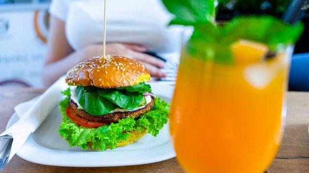 Vegetarian hamburger healthy vegan burger. Cute cheerful girl eating veggie sandwich with salad, avocado, vegetable. Vegan burger healthy diet food - Fotografie, Obrázek