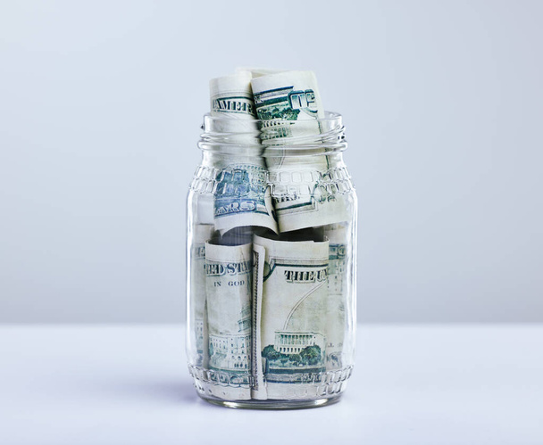 a jar filled with money against a grey background. - Fotografie, Obrázek