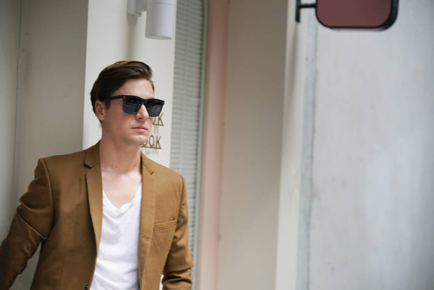 Portrait of a young man with sunglasses standing in urban background - Photo, image