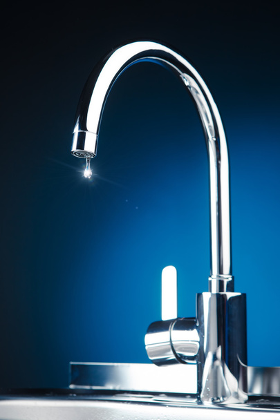 miscelatore rubinetto con goccia d'acqua, fondo blu
 - Foto, immagini