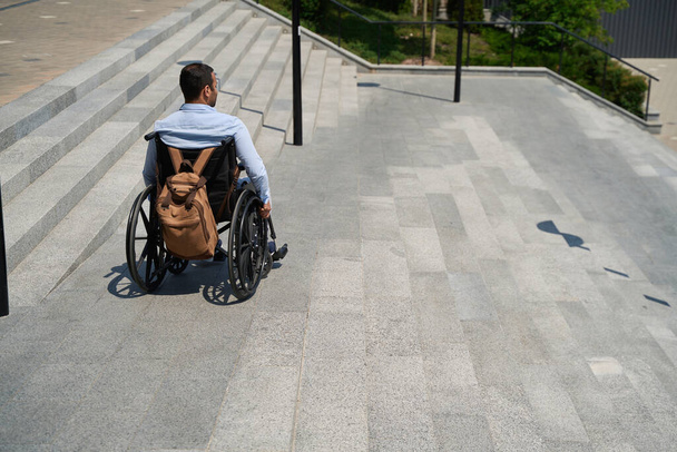 Back view of disabled male person going down external stairs in wheelchair - Fotografie, Obrázek