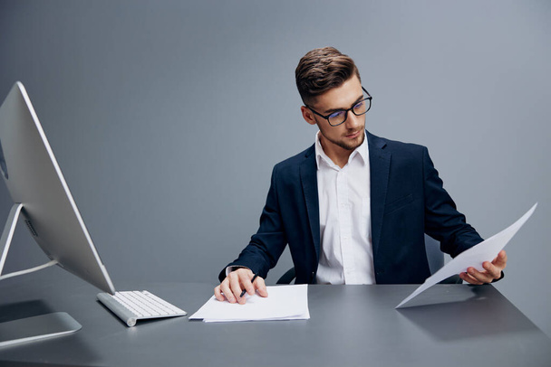 bel homme d'affaires portant des lunettes travaille devant un ordinateur isolé arrière-plan. Photo de haute qualité - Photo, image