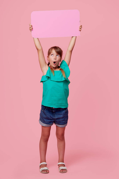 A cute laughing child girl is holding a signboard with an empty space for text. Advertising of childrens products and the announcement of discounts and sales - Fotó, kép
