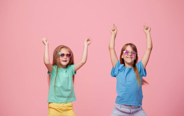 Cute adorable children having fun together with bright colorful t-shirts isolated on pink background - Valokuva, kuva