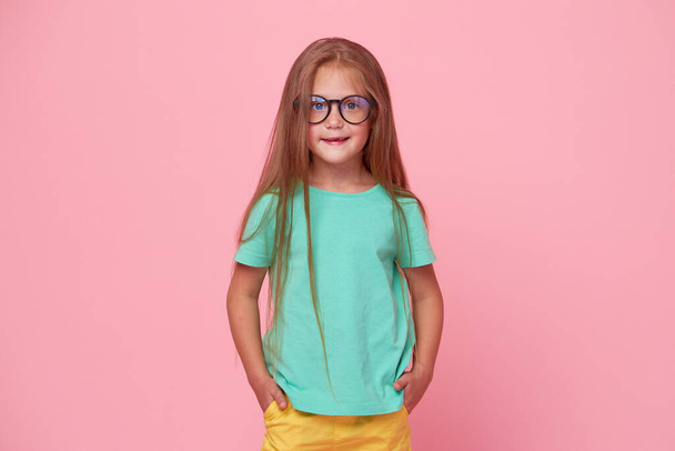 Portrait of cute toddler girl child bespectacled over pink background. Advertising childrens products. Funny face - Photo, Image