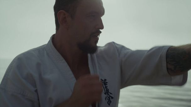 Aktiivinen urheilija koulutusta kädet taistelevat harjoituksia meriradalla lähikuva. Energinen urheilullinen mies treenaa taekwondoa auringonlaskun aikaan ulkona. Vahva parrakas taistelija harjoittelee taistelutekniikkaa luonnossa. - Valokuva, kuva